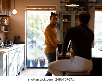 Man washing dishes while boyfriend using digital tablet at home kitchen - Powered by Shutterstock