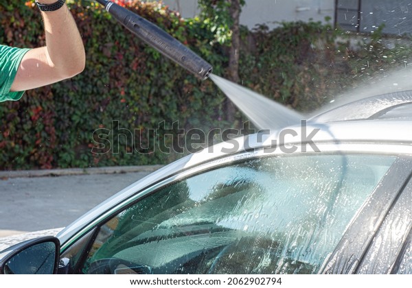 Man washing her car in car wash .A man washes a\
car in a manual car wash. 