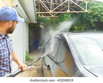 Man washing his black car near the house.   - Shutterstock ID 432058519