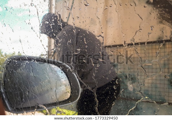 Man washing his car, close-up. Close-up of\
man holding a high-pressure water sprayer for door car washing.\
Abstract background.