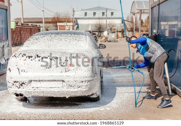 The man washing his car on self-service car wash.\
Express Car Wash