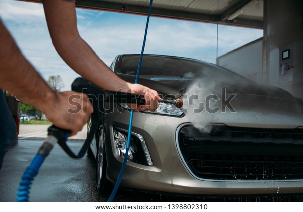 Man washing his car\
with pressure washer