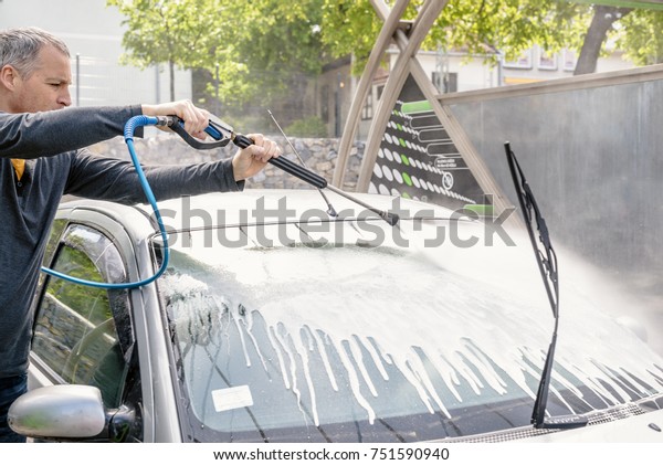 Man washing his car with
using a high pressure water jet. man washing his car with
compression water. Man washing his car in a self-service car wash
station