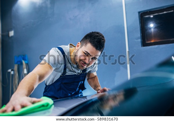 Man washing his car in a\
workshop.
