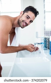 Man Washing His Face In Sink In Bathroom