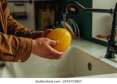 Man washing melon under tap at kitchen  - Powered by Shutterstock