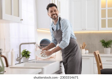 Man washing plate above sink in kitchen - Powered by Shutterstock