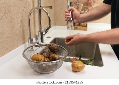 Man washing potatoes for lunch in a modern kitchen - Powered by Shutterstock