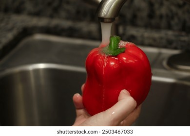 a man washing a red bell pepper under a faucet - Powered by Shutterstock