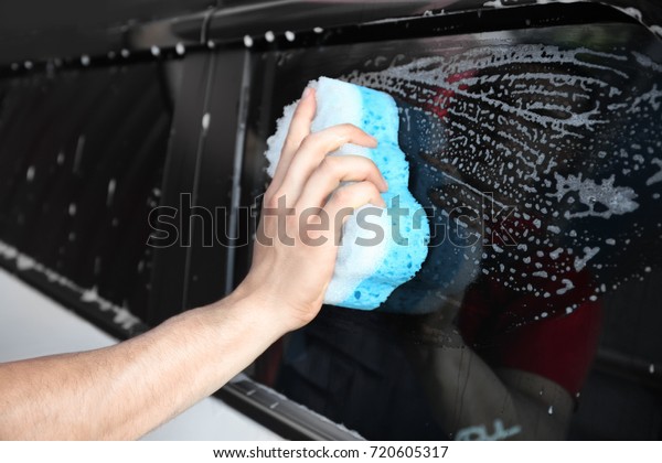 Man washing\
windows of car with sponge,\
closeup