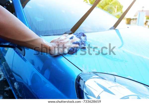 Man is washing and wipe\
car to clean.
