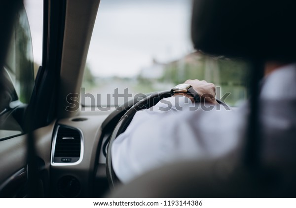 Man with a\
watch on hand at the wheel of a\
car