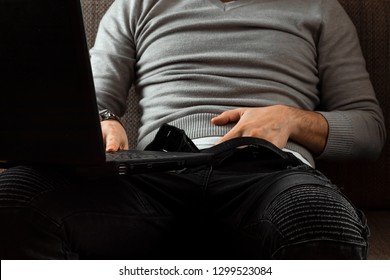 A Man Watches An Adult Video On A Laptop While Sitting On The Couch. The Concept Of Porn, Men's Needs, Pervert, Lust, Desire, Loneliness.