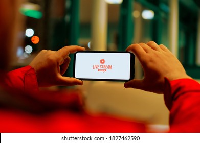 A man watches a live broadcast on a smartphone screen. Button Live Stream on the screen of a mobile phone - Powered by Shutterstock