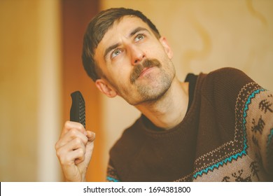 A Man Watches TV. A Man With A Remote Control In His Hands. Serious Man With A Remote Control In His Hands. Vintage Photo Processing.