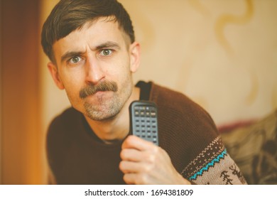 A Man Watches TV. A Man With A Remote Control In His Hands. Serious Man With A Remote Control In His Hands. Vintage Photo Processing.