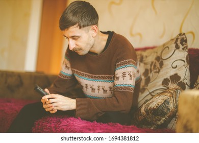 A Man Watches TV. A Man With A Remote Control In His Hands. Serious Man With A Remote Control In His Hands. Vintage Photo Processing.