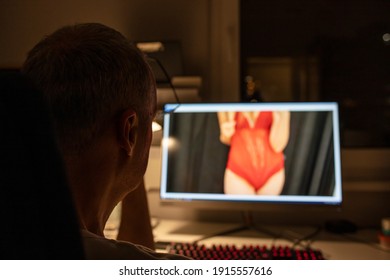 Man watching adult photo or video on PC display sitting in office chair. Concept of porn movies, home leisure. Man watches porn in his PC computer. Man watching porn on PC. Computer desktop adult only