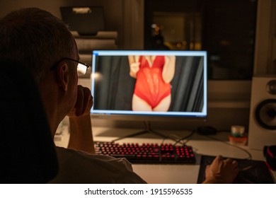 Man watching adult photo or video on PC display sitting in office chair. Concept of porn movies, home leisure. Man watches porn in his PC computer. Man watching porn on PC. Computer desktop adult only