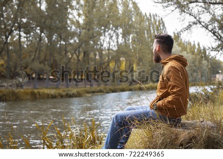 Similar – Man sitting by the river in fall