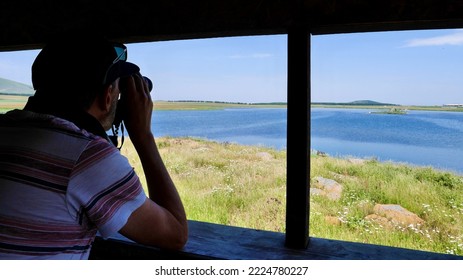 Man watching birds with binoculars from watchtower at Bughdasheni Lake in Javakheti volcanic plateau. Ninotsminda, Georgia. High quality photo