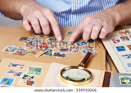 Man watching a collection of postage stamps isolated