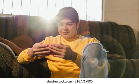 Man Watching Education And Business Videos On His Cell Phone Sitting In His Living Room. Young Man Watching Entertainment Videos. Cheerful Person Watching A Movie On His Cell Phone Screen