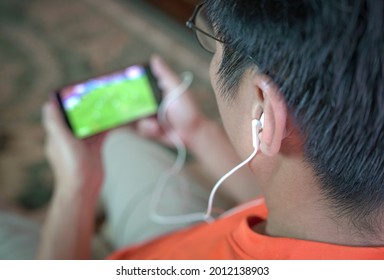 Man Watching Football And Sports On Mobile Phone. Selected Focus On Ear Phones.