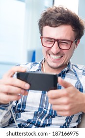 Man Watching Funny Video On His Phone With Earphones