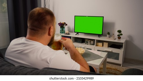 Man Watching Green Screen TV At Home. Drink Beer Eating Popcorn. Over The Shoulder Back View. Chroma Key.