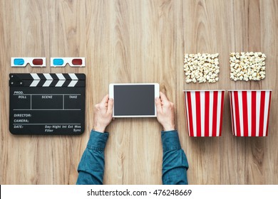 Man Watching Movies Streaming Online Using A Digital Tablet, Popcorn, 3D Glasses And Clapboard, Cinema And Entertainment Concept