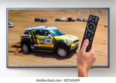 Man Is Watching Paris Dakar Racing On TV And Holding Tv Remote Controller In Hand