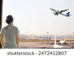 Man watching planes taking off from airport window. Aviation idea concept. Tourist or passenger waiting for his flight. Aircraft. Airlines. Horizontal photo. People, model, person. Sky. 