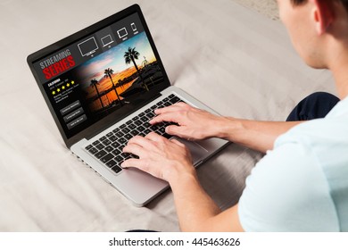 Man watching streaming tv series in a laptop computer sitting at home.