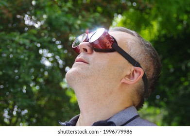 Man Watching A Sun Eclipse Through Safety Glasses. Looking At The Solar Phenomenon.