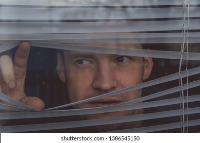 Man watching through window blinds
Portrait of young thoughtful male with brown eyes observing through window jalousie