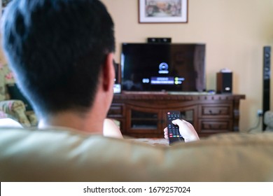 Man Watching Tv With Focus On His Hands On The Remote Control. Home Entertainment Or Stay At Home Concept.