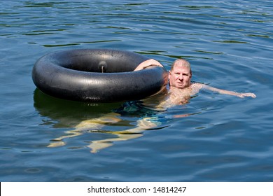 A Man In Water Floating With An Inner Tube