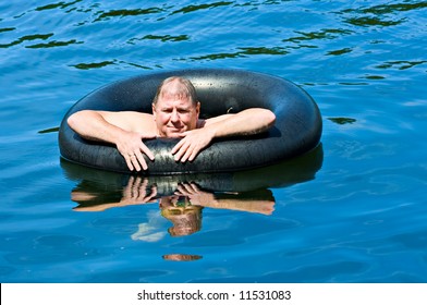 A Man In Water Floating On An Inner Tube