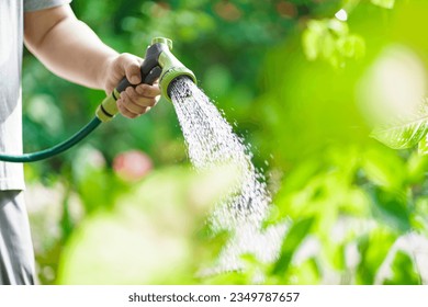 Man watering plants in his garden. Urban gardening watering fresh vegetables nature and plants care - Powered by Shutterstock