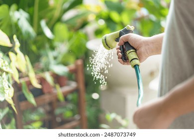 Man watering plants in his garden. Urban gardening watering fresh vegetables nature and plants care - Powered by Shutterstock