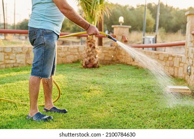 Man watering the lawn with a hose in the morning - Powered by Shutterstock