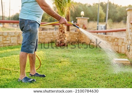 Man watering the lawn with a hose in the morning
