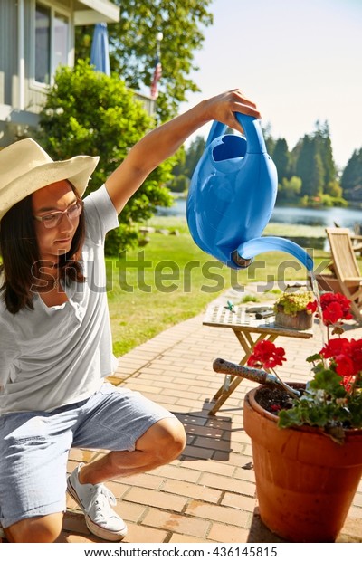 Man watering plants at lake house, Seattle,\
Washington, USA