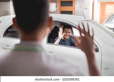 man wave good bye to his friend while driving a car