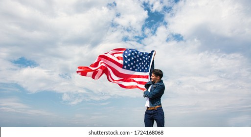 Man Waving American USA Flag Against Cloudy Blue Sky