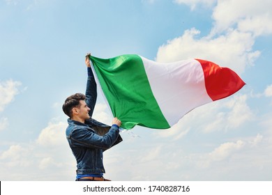 Man Waving Italian Flag Against Cloudy Blue Sky, Ational Holiday Of Italy, Postcard With Patriotic Symbols