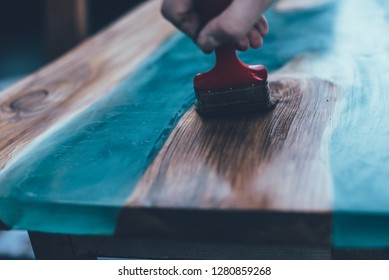 man waxing epoxy table. Custom furniture. Modern interior
