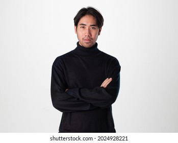 A man wear black turtleneck shirt do the crossarm action with serious face to the camera on white background.