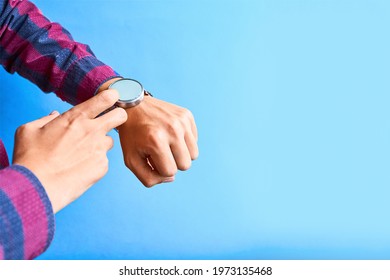 Man wear smart watch in everyday lifestyle. He using smart watch for omnichannel. Concept for business, multi payment. Modern digital gadget with empty display, copy space. Blue background. - Shutterstock ID 1973135468